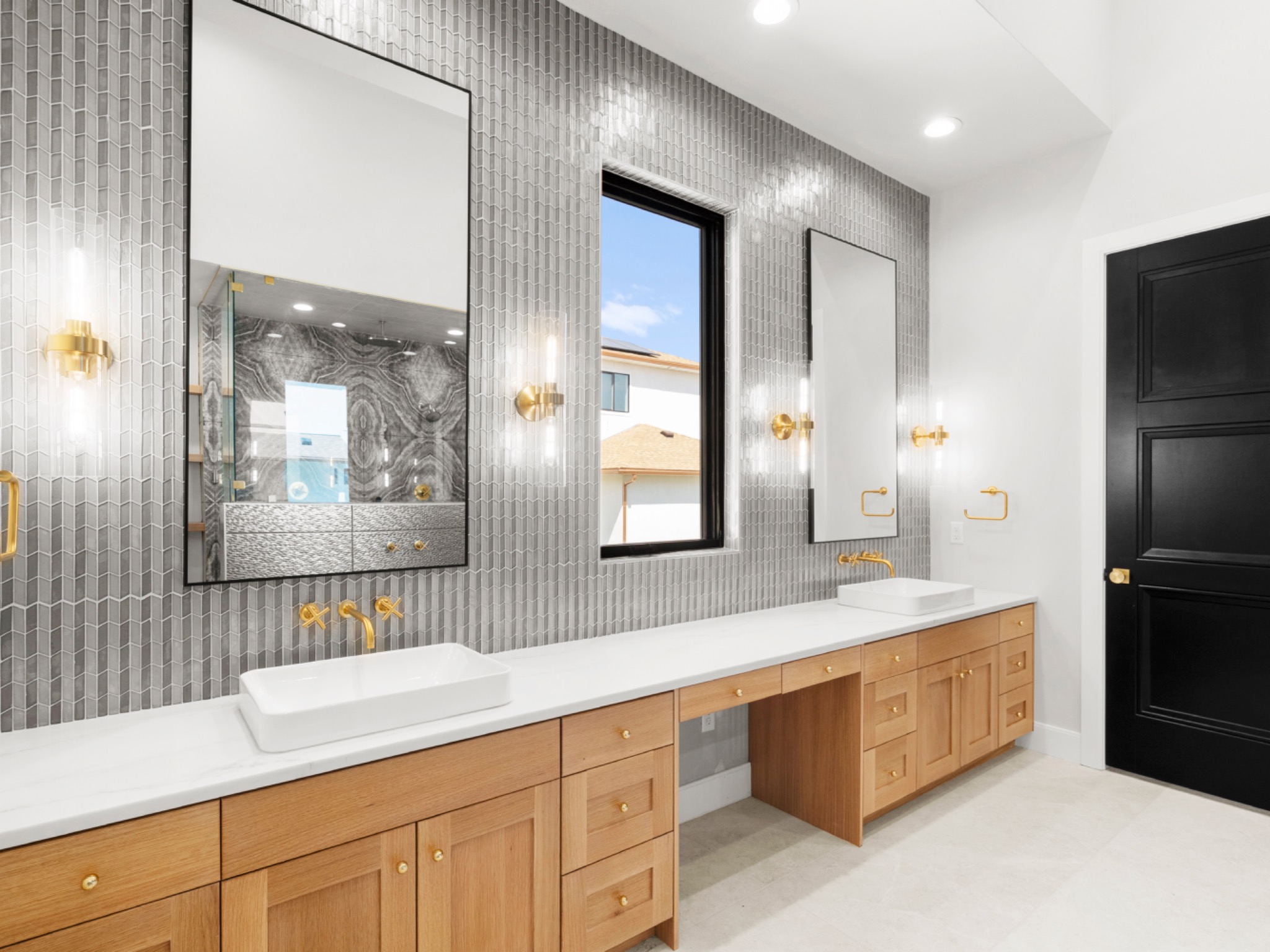 Primary bath with gold fixtures and gray tile